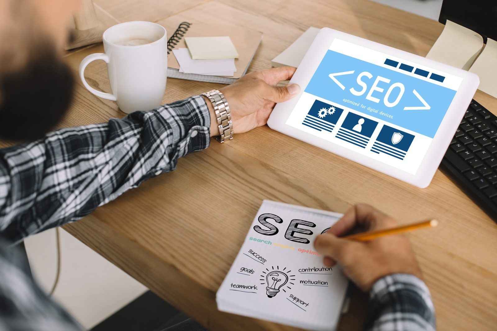 Marketer reviewing a site audit on a tablet while sketching SEO priorities on a notepad